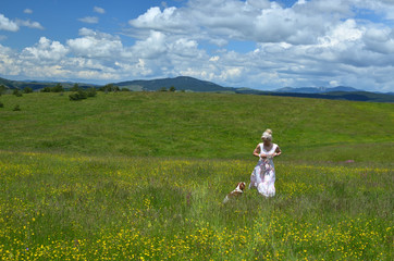 Fototapeta premium Woman walking with her dog over meadow on Zlatibor Mountain
