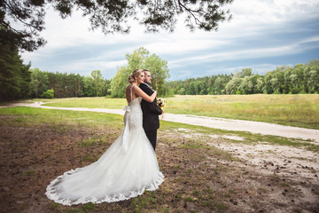 Bride and groom hugging after wedding ceremony on beautiful landscape background