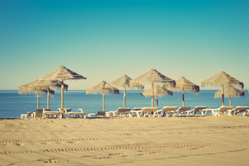 Beautiful view of beach with wicker umbrellas on the sunny blue sky outdoors background