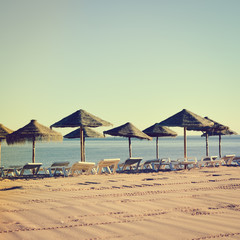 Beautiful view of beach with wicker umbrellas on the sunny blue sky outdoors background