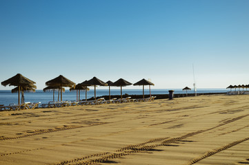 Beautiful view of beach with wicker umbrellas on the sunny blue sky outdoors background