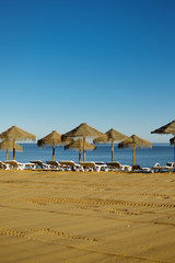 Beautiful view of beach with wicker umbrellas on the sunny blue sky outdoors background