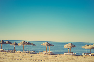 Beautiful view of beach with wicker umbrellas on the sunny blue sky outdoors background