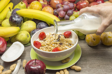 desayuno de cereales, frutas de temporada y leche fresca, persona vierte la leche en los cereales