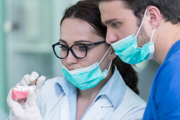 Dental prosthesis, dentures, prosthetics work. Prosthetics hands while working on the denture, false teeth, a study and a table with dental tools.