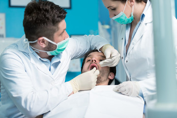 Dentistry education. Male dentist doctor teacher explaining treatment procedure to students group in dental clinic
