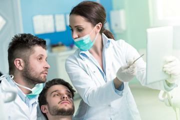 Dentistry education. Male dentist doctor teacher explaining treatment procedure to students group in dental clinic