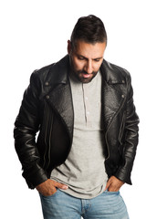 Trendy man standing against a white background wearing a black jacket and jeans, feeling relaxed and comfortable.