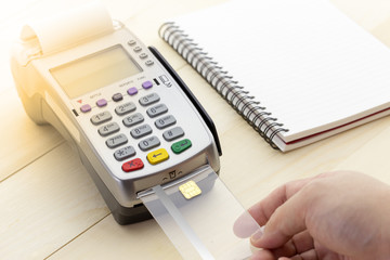 Cashier made a payment in store via EDC or credit card terminal with computer laptop, calculator, pen and pencil.