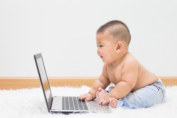 Cute baby boy with laptop on white carpet