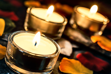 Three Romantic Candle Lights On Slate With Rose Petals And Leafs