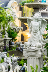 Fototapeta na wymiar Statue of Cupid in cozy garden./ Statue Cupid and waterfall in cozy garden.