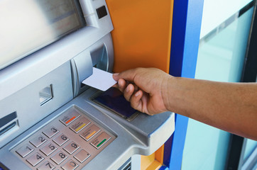 female hand inserting ATM card into ATM bank machine to withdraw money