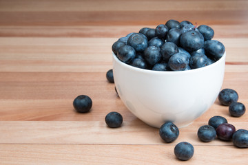 A bowl of blueberries on a wood table