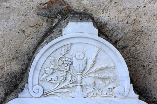 Sculptures. Chalice and a host on a tombstone. Cemetery Combloux.