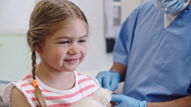 Smiling little girl sitting at doctors appointment, then wincing when getting a shot
