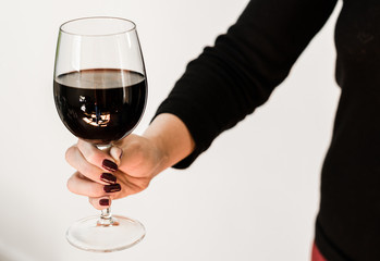 Holding a wine glass with red wine by woman with long fingers and nails