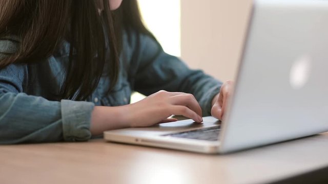 Teenage girls using a laptop sitting at table at home