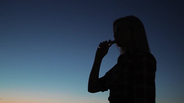 Silhouette of girl exhalation smoke from cigarette