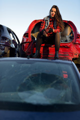 Fototapeta premium long-haired brunette girl posing in a car scrappage