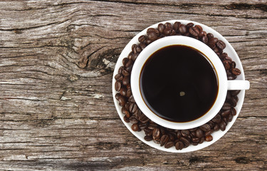 dark coffee with beans in white cup on ancient table