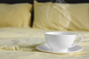 Fototapeta na wymiar hot coffee and smoke in white cup on bed