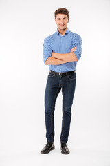 Full length of happy young man standing with arms crossed - obrazy, fototapety, plakaty