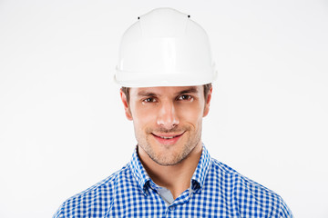 Closeup of smiling young man builder in hard hat