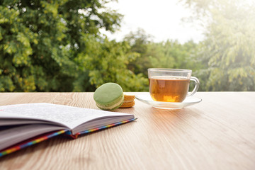 fresh tea in cup and book on garden table. Soft focus.