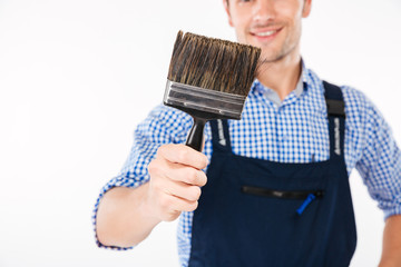 Cropped image of smiling male builder holding paint brush