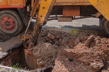 Excavator working on the Repair of pipe water and sewerage on road.