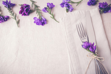 Purple flower table place setting on linen toning copy space background