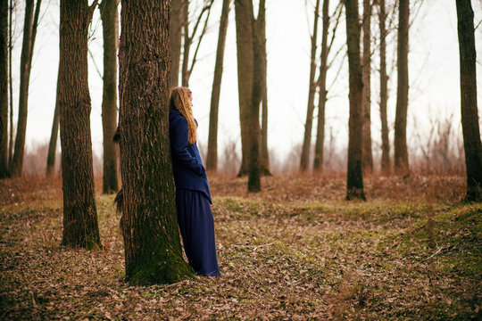 Lonely woman standing in forest in winter 