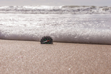 Compass on the sea sand at the beach, water in background