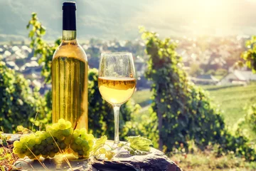 Cercles muraux Vin Bouteille et verre plein de vin blanc sur fond de vignoble
