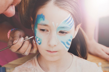 Female child face painting, making butterfly process