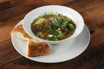 Chorba - traditional middle eastern soup in a white plate. Wooden background.