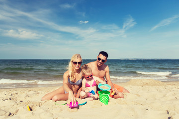 Fototapeta na wymiar happy family playing with sand toys on beach