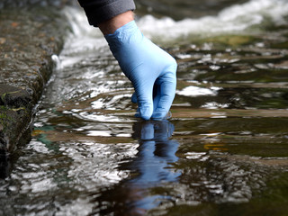 Water sample. Gloved hand into the water collecting tube. Analysis of water purity, environment,...