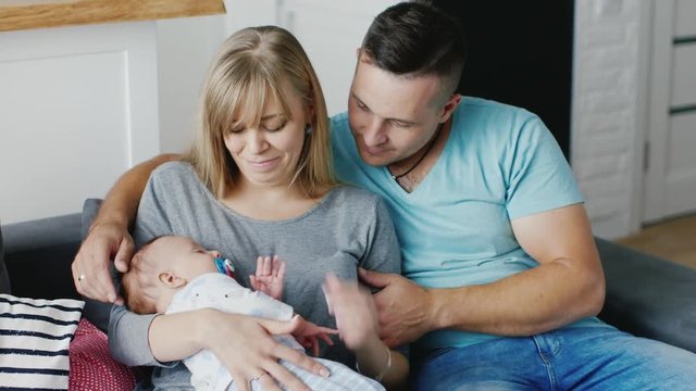 Mom and Dad soothe baby who cries on their hands. Happy young family