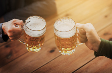 close up of hands with beer mugs at bar or pub