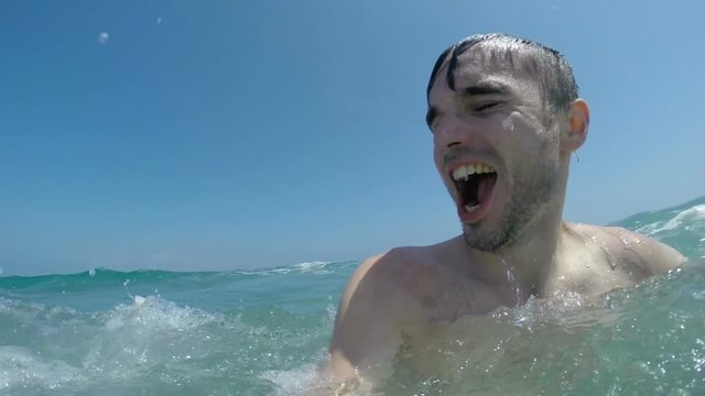 Slow motion of ecstatic man enjoying sea waves.