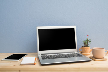 Office desk with laptop, Note paper, Euphorbia milii flower on terracotta flower pot and blank screen tablet.