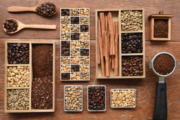 Coffee beans with ground coffee in wooden spoon and cinnamon on wooden background
