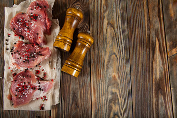 Top view raw pork chop steak and garlic, pepper on wooden background.