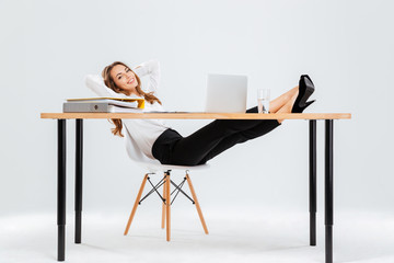 Relaxed young businesswoman sitting and relaxing with legs on table