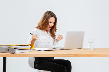 Angry young businesswoman using laptop and shouting