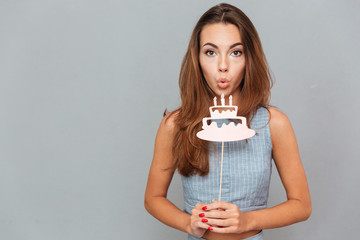 Pretty cute young woman blowing on birthday cake props