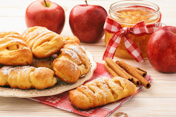 Fresh yeast buns with apple jam and cinnamon on white wooden background.