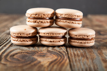 Chocolate macaroons and black chocolate on old wooden table